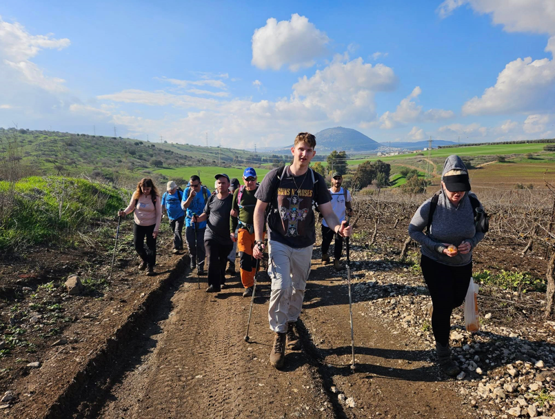 בתמונה צעיר צועד בטיול ואחריו קבוצת מטיילי מגדל אור שביל ישראל 