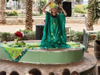 פרח אדום גדול על רקע צמחייה ירוקה, מימין ברווז, כבשה, עורב